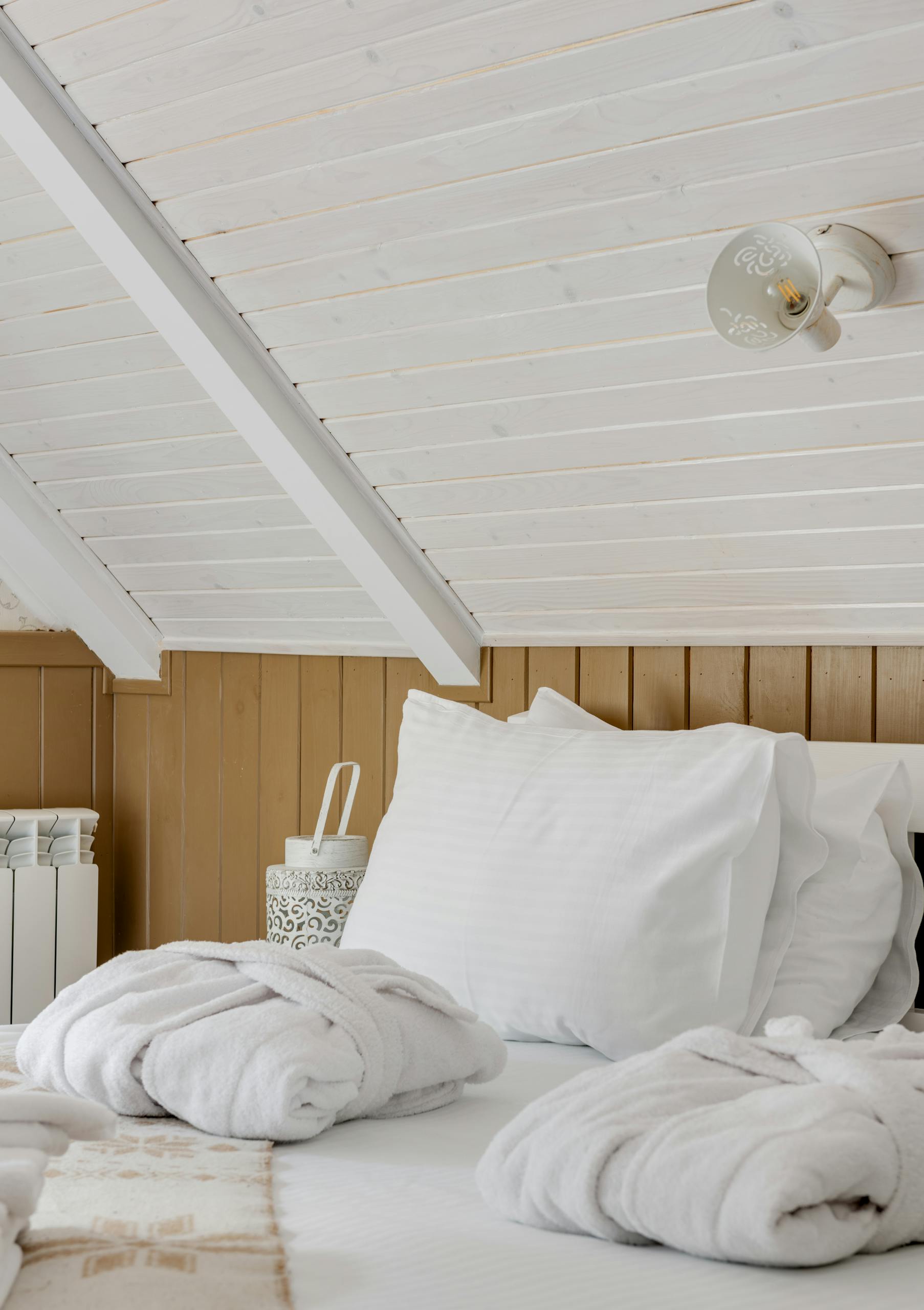 Inviting attic bedroom featuring crisp white bedding and soft natural light, perfect for relaxation.